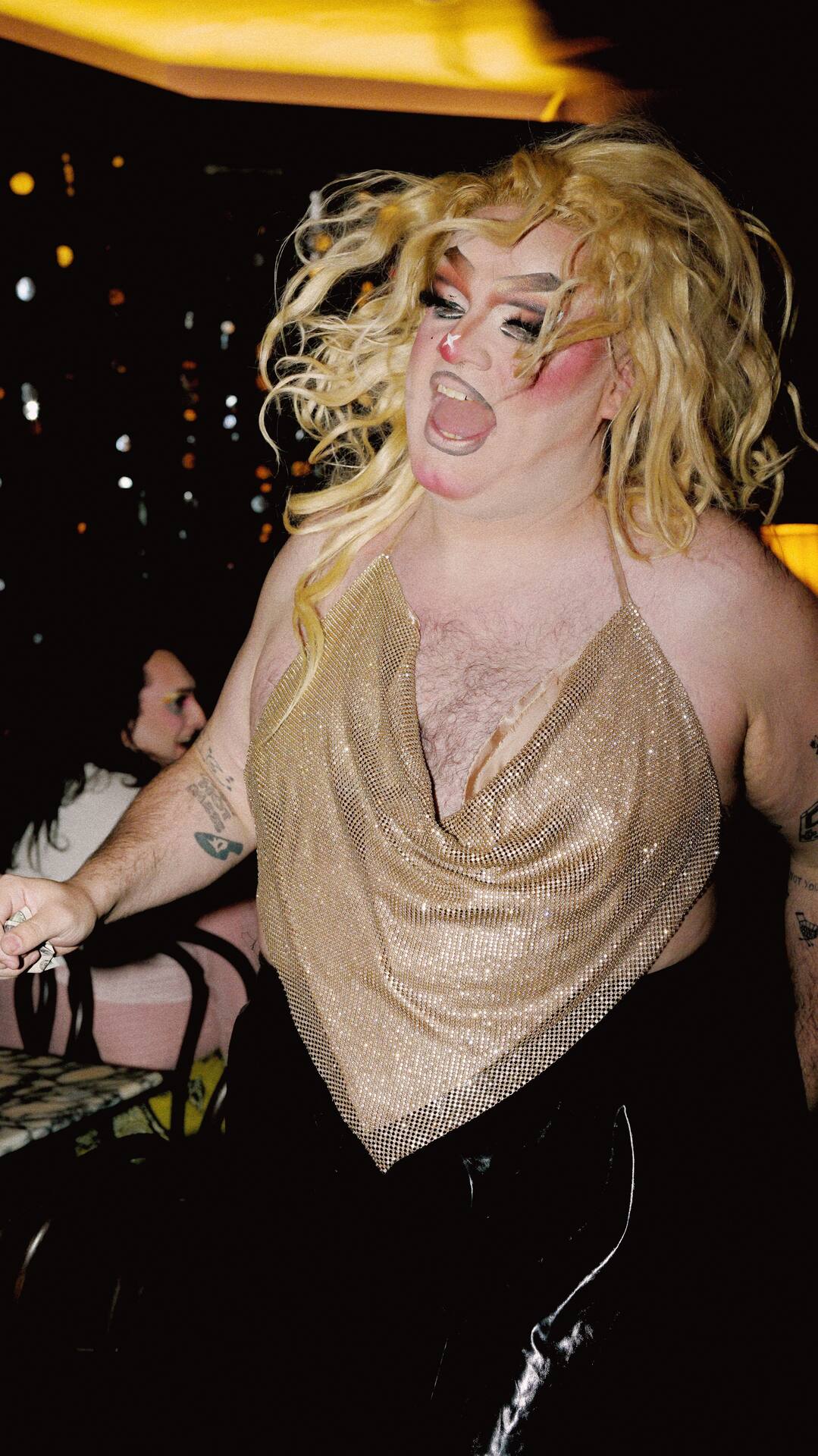 Zalika Parsons performing in gold chainmail at Apartment 5, crowd and cocktails in the background